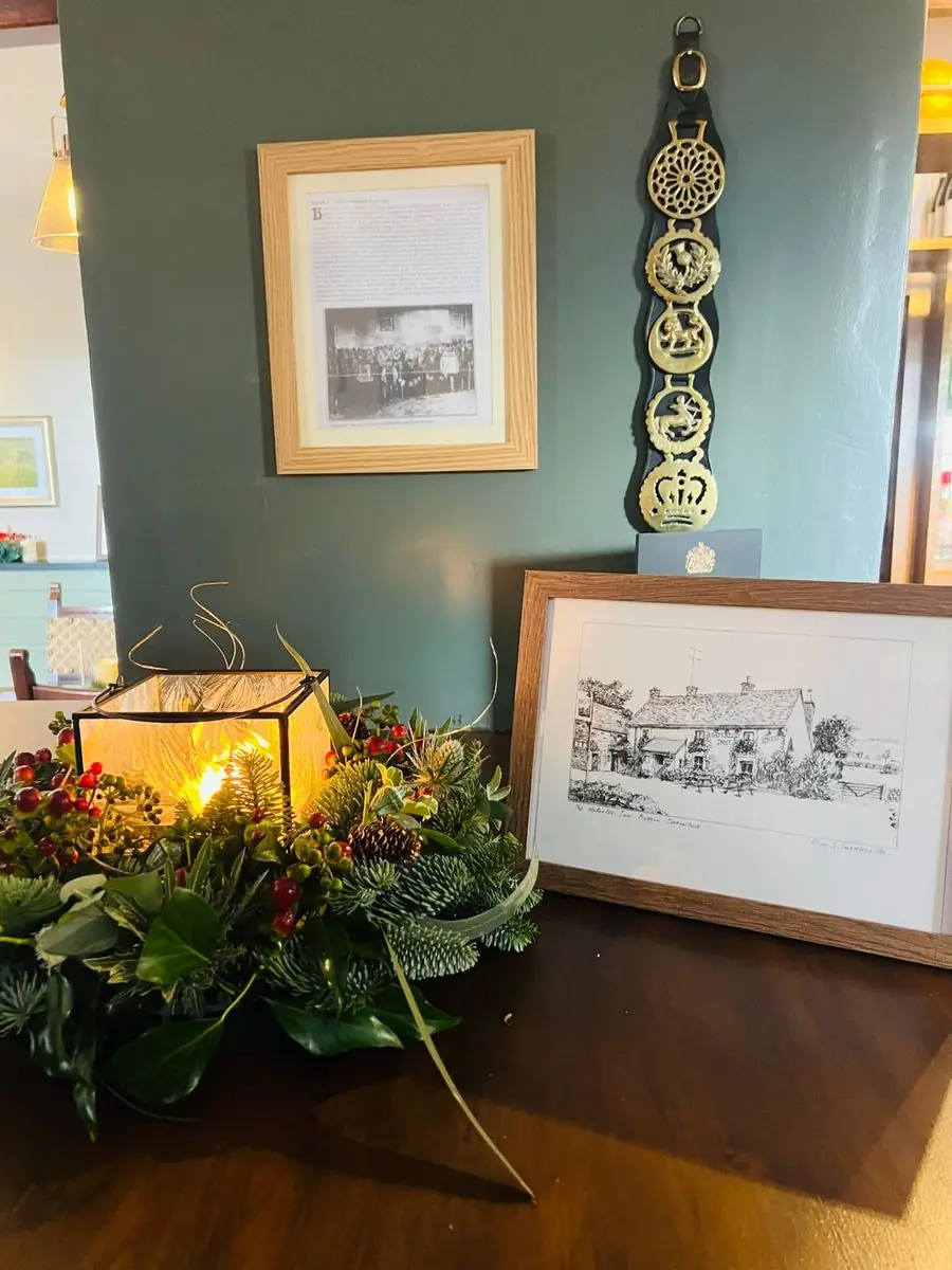 Heritage corner at The Waterloo Inn featuring a framed sketch of the pub, horse brasses and historical photos