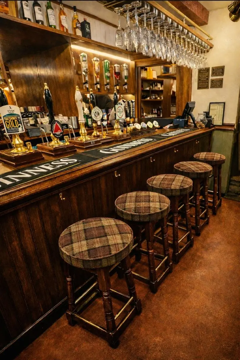 Traditional wooden bar with brass beer pumps and tartan stools